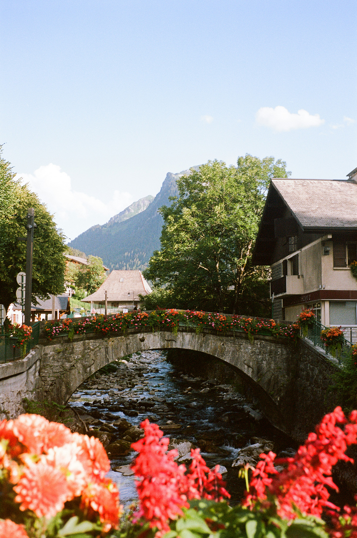beautiful historic bridge in central Morzine in summer with flowers around