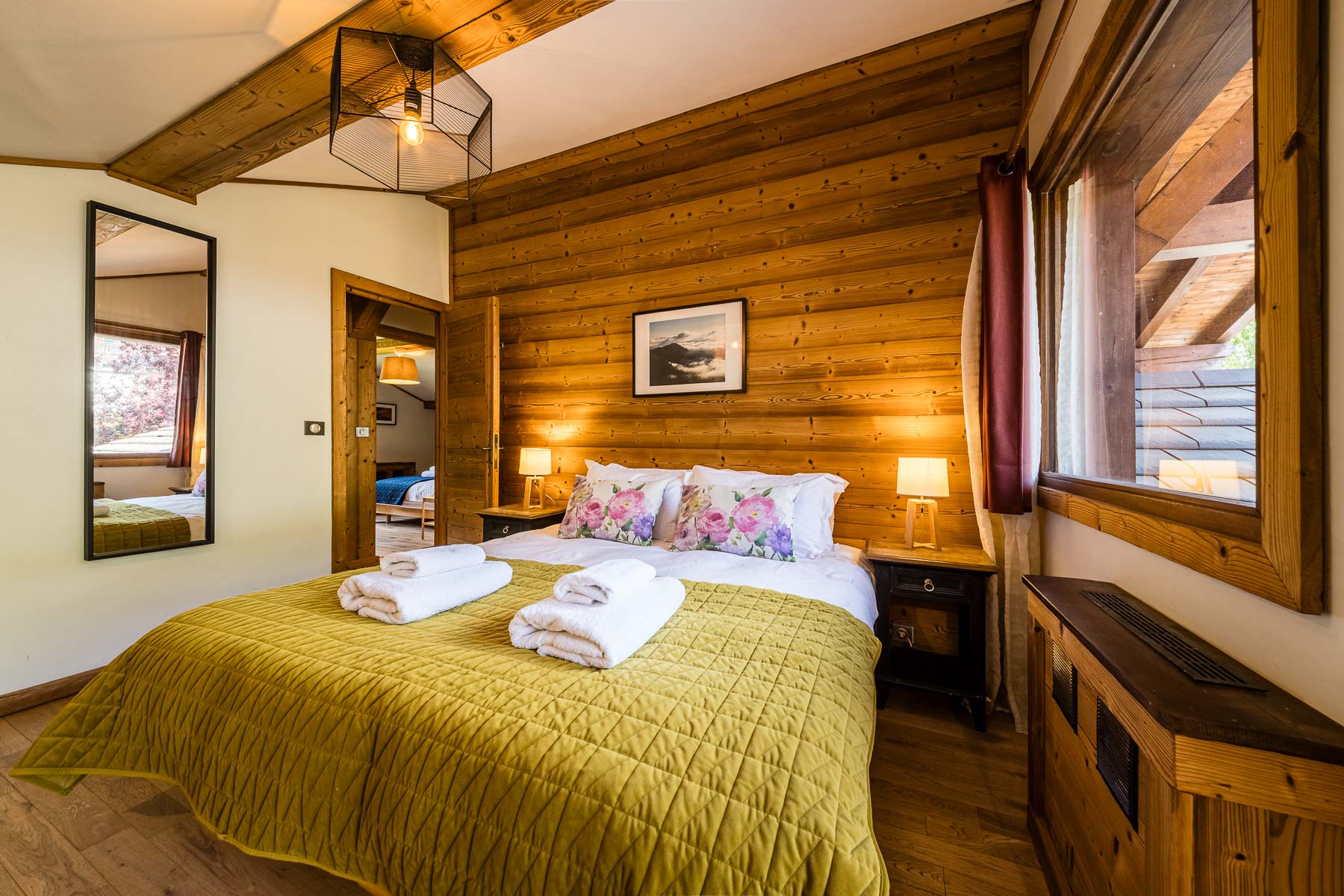 Double bedroom with green bedding and warm timber interiors at Chalet Coffy in Morzine