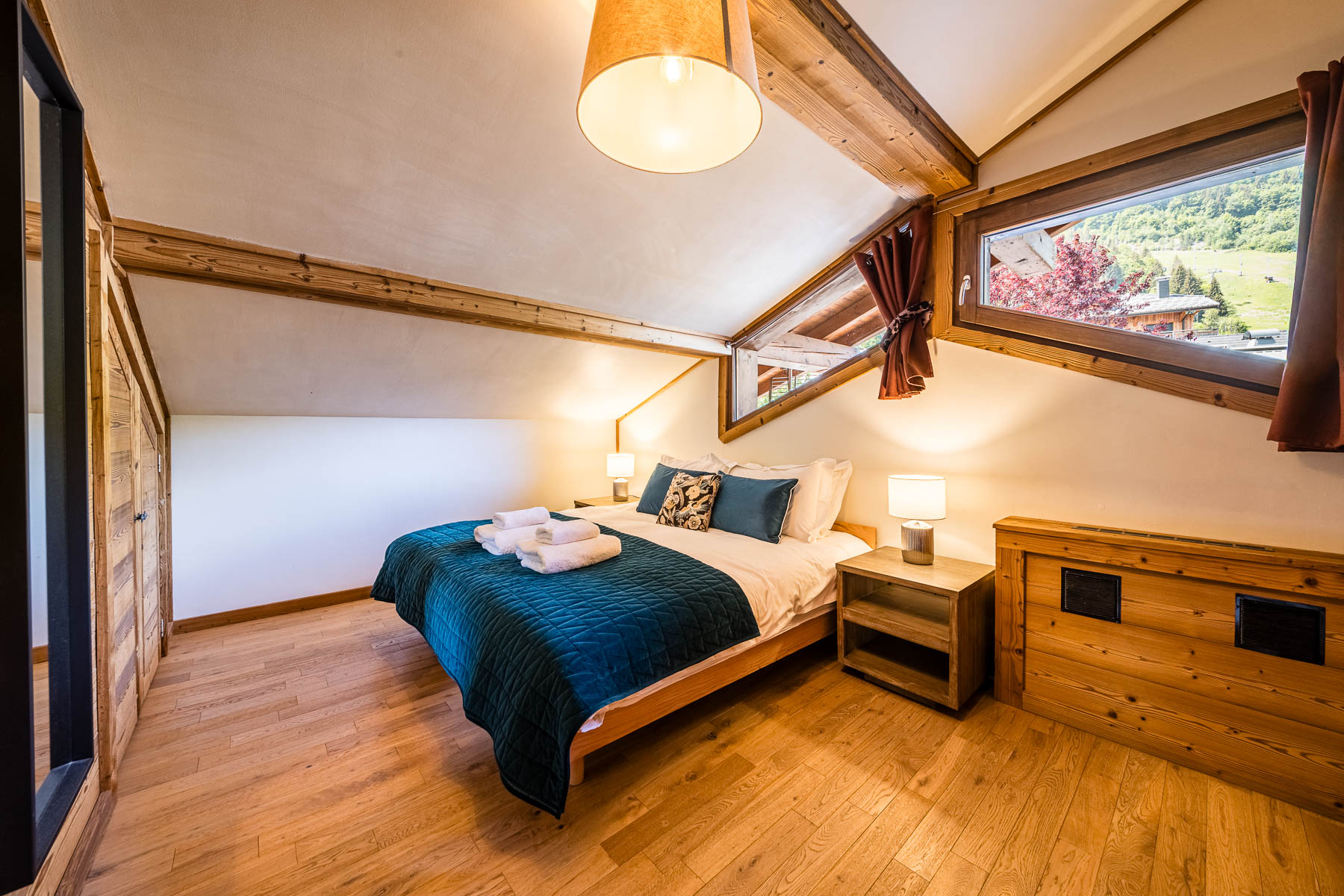 Cosy double bedroom with blue bedding, exposed beams and alpine views at Chalet Coffy