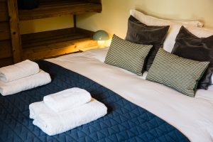 Double bedroom with blue quilted bedding, striped cushions and fresh towels at Chalet Coffy