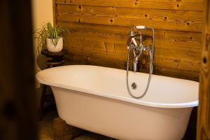 Freestanding roll-top bath with traditional chrome taps and timber wall at Chalet Coffy