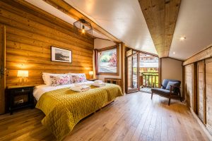 Spacious double bedroom at Chalet Coffy with wooden walls, balcony access and mountain views