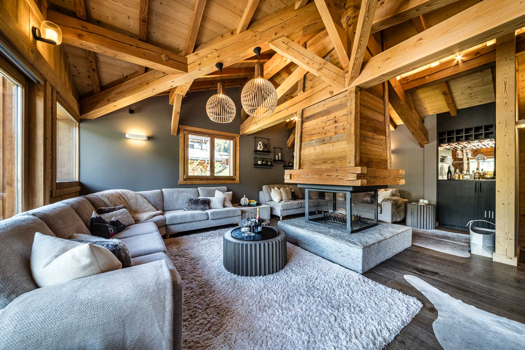 Open-plan lounge with central fireplace at Chalet Floralies
