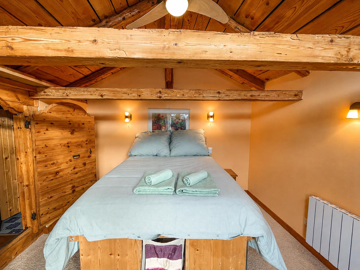 Double bedroom with exposed timber beams at Chalet Greniette