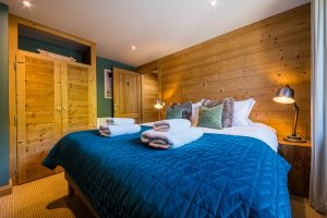 Double bedroom with wood-panelled walls at Chalet La Grange